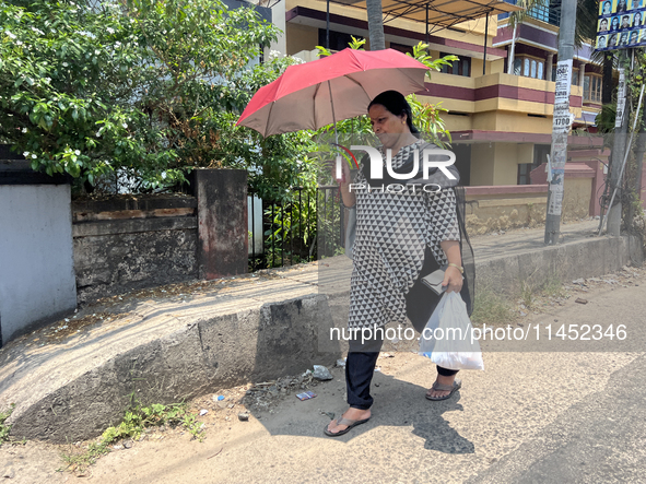 A woman is using an umbrella to protect herself from the hot sun in Thiruvananthapuram (Trivandrum), Kerala, India, on March 31, 2024. 