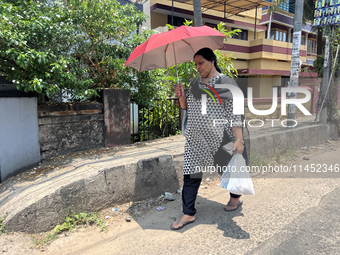 A woman is using an umbrella to protect herself from the hot sun in Thiruvananthapuram (Trivandrum), Kerala, India, on March 31, 2024. (