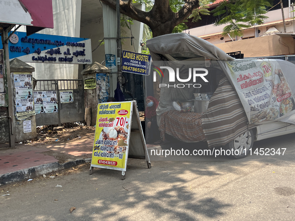 A woman is selling pre-made biryani from the back of a vehicle along the roadside in Thiruvananthapuram (Trivandrum), Kerala, India, on Marc...