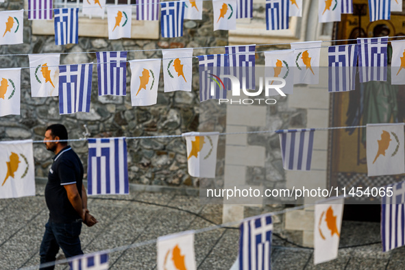 A man is walking in the monastery yard under Greek and Cypriot flags in Kykkos, Cyprus, on August 4, 2024. President of Cyprus Nikos Christo...