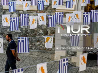 A man is walking in the monastery yard under Greek and Cypriot flags in Kykkos, Cyprus, on August 4, 2024. President of Cyprus Nikos Christo...