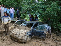 A man is using a shovel to remove debris as vehicles remain buried after a cloudburst near Cherwan Padabal area in central Kashmir's Ganderb...