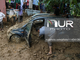 A man is using a shovel to remove debris as vehicles remain buried after a cloudburst near Cherwan Padabal area in central Kashmir's Ganderb...