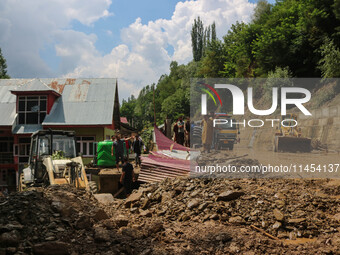 People are standing on debris after a cloudburst near Cherwan Padabal area in central Kashmir's Ganderbal district, some 42 kilometers from...