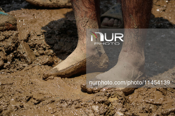 A man is standing in the mud after a cloudburst near Cherwan Padabal area in central Kashmir's Ganderbal district, some 42 kilometers from S...