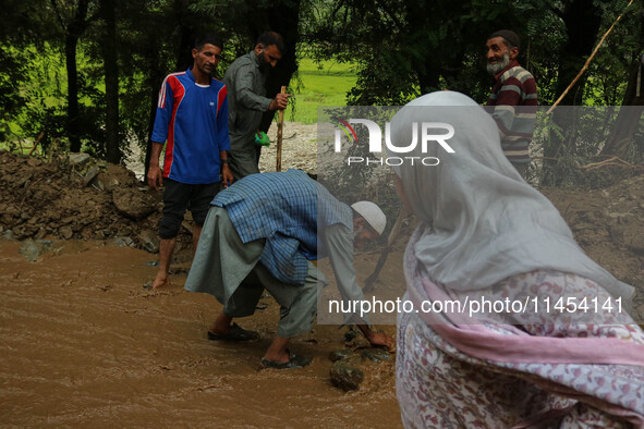 Roads and Building Department (R&B) workers are clearing the road after a cloudburst near Cherwan Padabal area in central Kashmir's Ganderba...