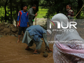 Roads and Building Department (R&B) workers are clearing the road after a cloudburst near Cherwan Padabal area in central Kashmir's Ganderba...