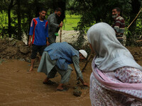 Roads and Building Department (R&B) workers are clearing the road after a cloudburst near Cherwan Padabal area in central Kashmir's Ganderba...