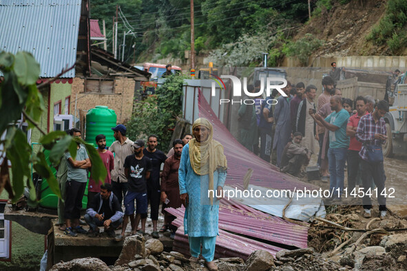 A Kashmiri woman is standing on debris after a cloudburst near Cherwan Padabal area in central Kashmir's Ganderbal district, some 42 kilomet...