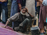 An elderly man is looking on as excavators are removing debris after a cloudburst near Cherwan Padabal area in central Kashmir's Ganderbal d...