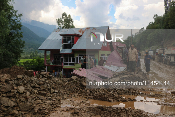 People are standing on debris after a cloudburst near Cherwan Padabal area in central Kashmir's Ganderbal district, some 42 kilometers from...