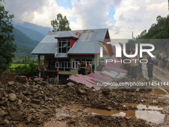 People are standing on debris after a cloudburst near Cherwan Padabal area in central Kashmir's Ganderbal district, some 42 kilometers from...