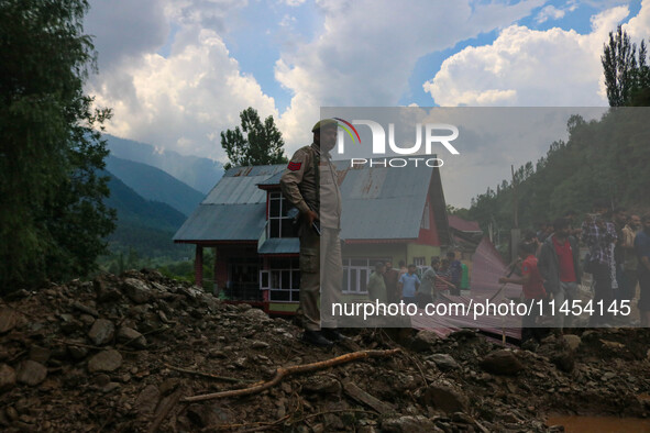 An Indian policeman is standing on debris after a cloudburst near Cherwan Padabal area in central Kashmir's Ganderbal district, some 42 kilo...