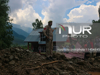 An Indian policeman is standing on debris after a cloudburst near Cherwan Padabal area in central Kashmir's Ganderbal district, some 42 kilo...