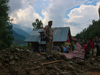 An Indian policeman is standing on debris after a cloudburst near Cherwan Padabal area in central Kashmir's Ganderbal district, some 42 kilo...