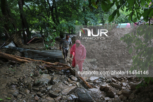 People are walking over the debris after a cloudburst near Cherwan Padabal area in central Kashmir's Ganderbal district, some 42 kilometers...