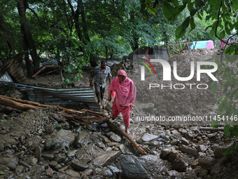 People are walking over the debris after a cloudburst near Cherwan Padabal area in central Kashmir's Ganderbal district, some 42 kilometers...