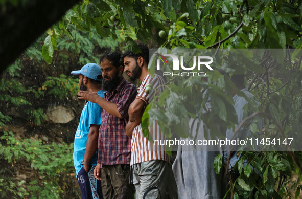 People are looking on as excavators are removing debris after a cloudburst near Cherwan Padabal area in central Kashmir's Ganderbal district...