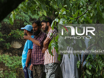 People are looking on as excavators are removing debris after a cloudburst near Cherwan Padabal area in central Kashmir's Ganderbal district...