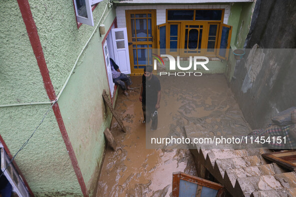 A man is standing in the mud after a cloudburst near Cherwan Padabal area in central Kashmir's Ganderbal district, some 42 kilometers from S...