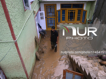 A man is standing in the mud after a cloudburst near Cherwan Padabal area in central Kashmir's Ganderbal district, some 42 kilometers from S...