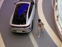 A man is walking past a BYD auto as 70 models from auto dealers like Tesla, Audi, Hongqi, SAIC Volkswagen, and Jiyue Nio are on display duri...