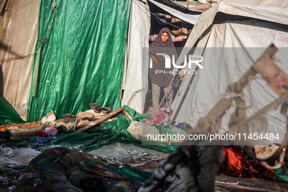 Palestinians are looking on from a tent at the site of an Israeli strike on a tent camp for displaced people, amid the Israel-Hamas conflict...