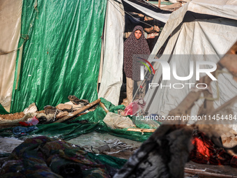 Palestinians are looking on from a tent at the site of an Israeli strike on a tent camp for displaced people, amid the Israel-Hamas conflict...