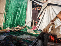 Palestinians are looking on from a tent at the site of an Israeli strike on a tent camp for displaced people, amid the Israel-Hamas conflict...