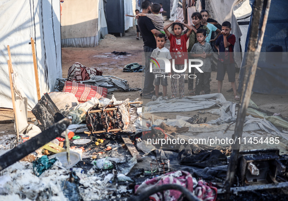 Palestinian children are inspecting the site of an Israeli strike on a tent camp for displaced people, amid the Israel-Hamas conflict, in De...