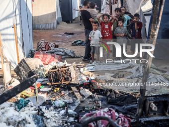 Palestinian children are inspecting the site of an Israeli strike on a tent camp for displaced people, amid the Israel-Hamas conflict, in De...