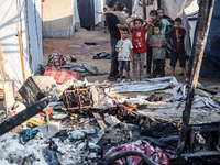 Palestinian children are inspecting the site of an Israeli strike on a tent camp for displaced people, amid the Israel-Hamas conflict, in De...