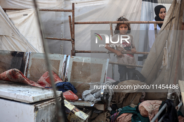 Palestinians are looking on from a tent at the site of an Israeli strike on a tent camp for displaced people, amid the Israel-Hamas conflict...