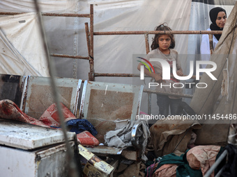 Palestinians are looking on from a tent at the site of an Israeli strike on a tent camp for displaced people, amid the Israel-Hamas conflict...