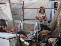 Palestinians are looking on from a tent at the site of an Israeli strike on a tent camp for displaced people, amid the Israel-Hamas conflict...