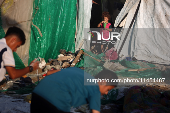 Palestinians are looking on from a tent at the site of an Israeli strike on a tent camp for displaced people, amid the Israel-Hamas conflict...