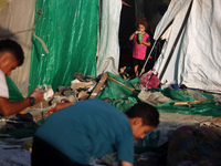 Palestinians are looking on from a tent at the site of an Israeli strike on a tent camp for displaced people, amid the Israel-Hamas conflict...