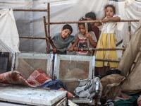 Palestinian children are inspecting the site of an Israeli strike on a tent camp for displaced people, amid the Israel-Hamas conflict, in De...