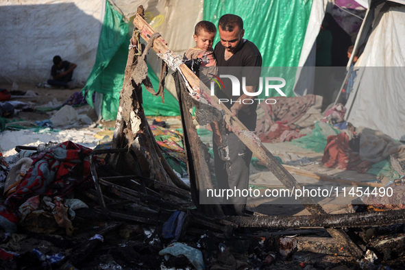 A Palestinian man is inspecting the site of an Israeli strike on a tent camp for displaced people, amid the Israel-Hamas conflict, in Deir A...