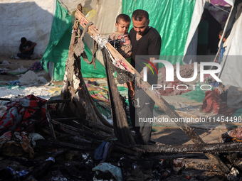 A Palestinian man is inspecting the site of an Israeli strike on a tent camp for displaced people, amid the Israel-Hamas conflict, in Deir A...