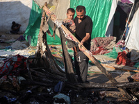 A Palestinian man is inspecting the site of an Israeli strike on a tent camp for displaced people, amid the Israel-Hamas conflict, in Deir A...