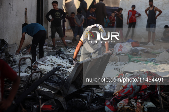 Palestinians are inspecting the site of an Israeli strike on a tent camp for displaced people, amid the Israel-Hamas conflict, in Deir Al-Ba...