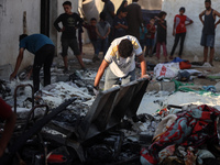 Palestinians are inspecting the site of an Israeli strike on a tent camp for displaced people, amid the Israel-Hamas conflict, in Deir Al-Ba...