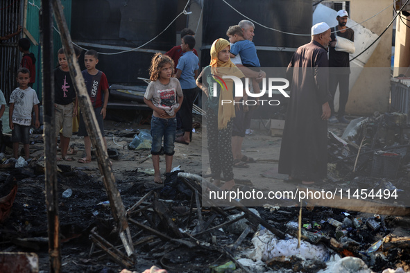 Palestinians are inspecting the site of an Israeli strike on a tent camp for displaced people, amid the Israel-Hamas conflict, in Deir Al-Ba...