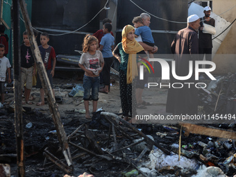 Palestinians are inspecting the site of an Israeli strike on a tent camp for displaced people, amid the Israel-Hamas conflict, in Deir Al-Ba...