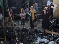 Palestinians are inspecting the site of an Israeli strike on a tent camp for displaced people, amid the Israel-Hamas conflict, in Deir Al-Ba...