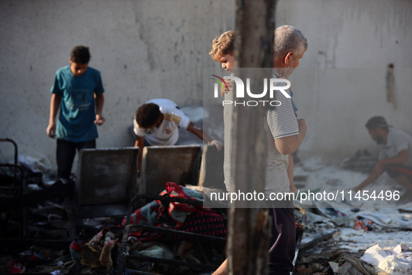 Palestinians are inspecting the site of an Israeli strike on a tent camp for displaced people, amid the Israel-Hamas conflict, in Deir Al-Ba...