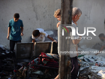 Palestinians are inspecting the site of an Israeli strike on a tent camp for displaced people, amid the Israel-Hamas conflict, in Deir Al-Ba...