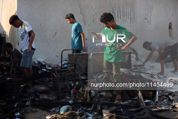 Palestinians are inspecting the site of an Israeli strike on a tent camp for displaced people, amid the Israel-Hamas conflict, in Deir Al-Ba...