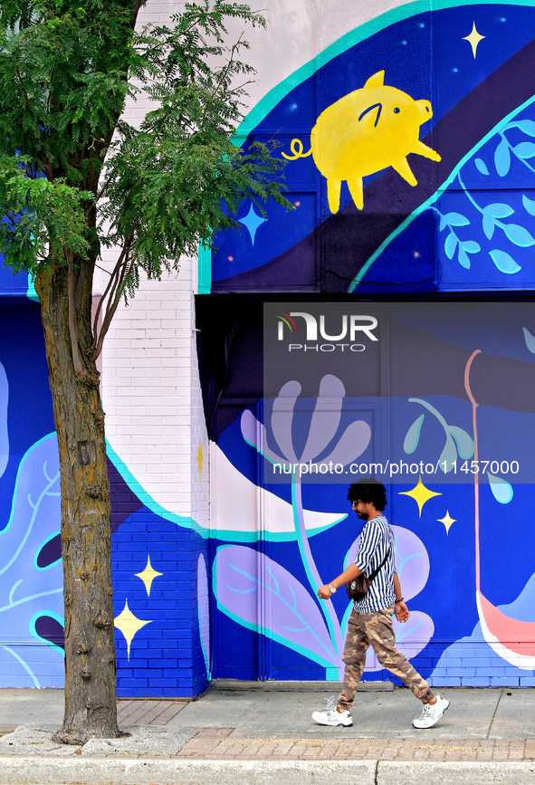 A person is walking in front of a colorful mural near the downtown Brampton, Ontario, transit terminal on Monday, August 5, 2024. 